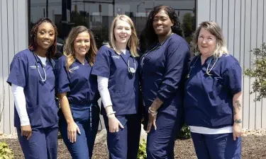 Herzing practical nursing students smiling outside campus